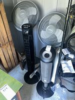 Two Lasko pedestal fans and one tower fan grouped together
