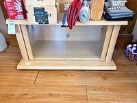 Front view of light maple media console with glass doors closed