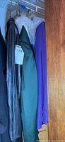 Closet view showing leather jacket, green and purple suit jackets on hangers