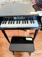 Full view of Schoenhut toy piano on legs with matching bench