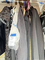 Closet view showing sequined dress, plastic-covered garment and several black blazers/coats on hangers