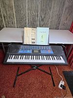 Full view of keyboard on stand with songbooks and adapter