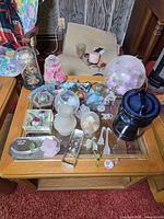 Coffee table view showing majority of glass figurines, paperweights, domes and blue lidded jar