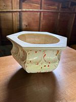 Front view of cream ceramic vessel with orange speckles