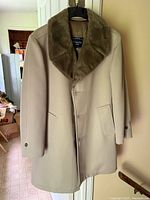 Front view of beige overcoat with brown faux fur collar hanging on hanger