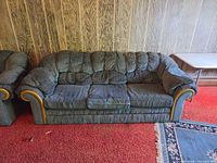 Front view of three-seat sofa showing fabric, cushions, wood-trimmed arms, skirt