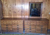 Two matching wooden dressers side by side with mirror resting on right dresser
