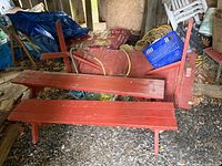 Overall view of red wooden picnic table components and two benches