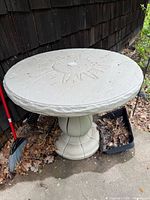 Round gray plastic pedestal outdoor table with sunburst design and umbrella hole