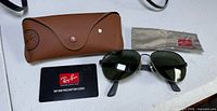 Sunglasses, case, card and cloth displayed on table
