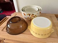 Group shot of all five bowls: three Hall Autumn Leaf, one amber glass, one yellow Pyrex