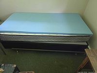 Twin bed showing blue foam topper on mattress and frame