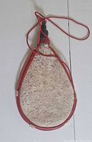 Full view of hair-on hide wineskin with red leather trim and cord
