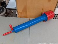 Full view of metal pesticide duster showing blue barrel, red reservoir and plunger handle