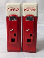 Front view of both Coca-Cola Vendo shakers showing logos, coin slots, dispenser openings