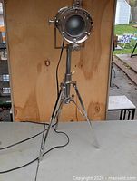 Full view of chrome tripod spotlight lamp