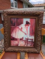 Full view of framed ballerina painting resting on chairs