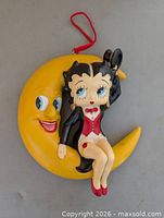 Front view of Betty Boop resin wall hanging on crescent moon with red cord