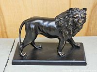 Left front view of bronzed lion on base