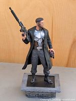 Full view of Punisher statue on base holding rifle and helmet