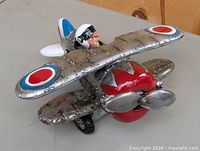 Front left view of silver ceramic biplane bank showing red nose, propeller, pilot figure and roundel wing markings