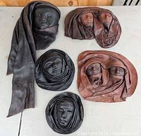 All five leather face plaques laid out on table