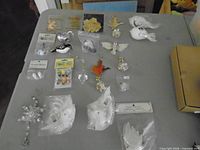 Entire assortment laid out on table including packaged items, feathered birds, metal pieces and glass drop