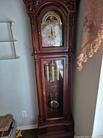 Full view of grandfather clock showing mahogany case, glass door and side panel