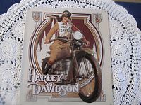 Cream sign with female rider on vintage Harley