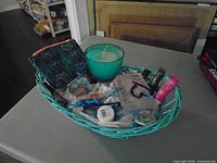 First basket with teal glass candle, zip pouch and assorted sample cosmetics visible
