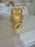 Front view of gold resin coin bank showing facial features and black character detail