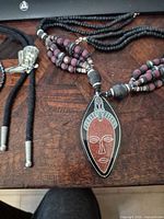 Overview of multistrand mask necklace alongside bolo tie segment