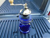 Grinder full view showing body, brass lid, crank