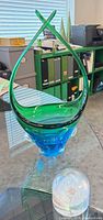 Hand-blown green and blue teardrop glass accent on table