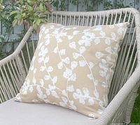 Square tan cushion with white blossom design on patio chair