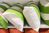 Four green and white striped lumbar cushions on shelf, zippered ends visible