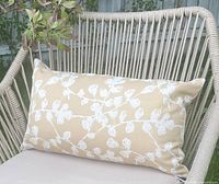 Tan cushion with white blossom pattern placed on outdoor chair