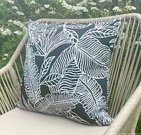 Outdoor chair displaying one cushion cover with black base and white tropical leaf design