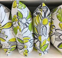Edge view of four identical floral outdoor cushions showing fabric pattern and thickness