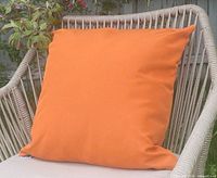 Single orange cushion on outdoor chair showing front and texture