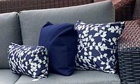 Three stuffed examples of the cushion covers on patio sofa: navy blossom rectangular, navy cover profile, navy blossom square