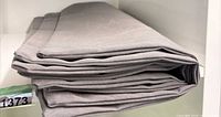Stack of four grey outdoor cushion covers folded