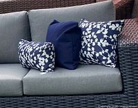 Three pillow covers displayed on outdoor sofa showing solid navy and blossom designs