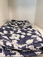 Stack of navy cushion covers with white blossom print folded to show fabric and pattern