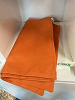 Folded orange cushion covers showing fabric and zipper