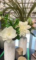 Two patterned ceramic vases with faux florals beside two metallic lidded containers