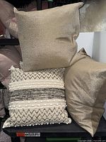 Four pillows arranged; two metallic gold textured and two cream woven