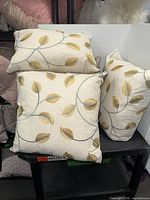 Three pillows displayed on shelving, showing embroidery pattern and fabric