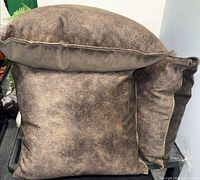 Front view of two pillows showing distressed brown faux-leather texture