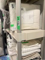 full view of five-tier white plastic shelf loaded with linens showing overall structure and color